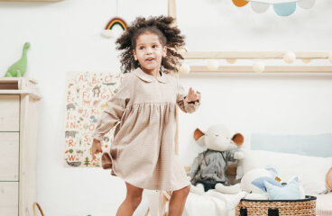 Mother and toddler exploring a learning-rich home corner filled with books, wooden toys, and natural light.